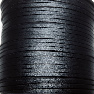 May include: A close-up of a spool of black leather cord. The cord is wound tightly and has a smooth, textured surface.