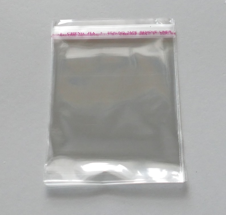 Może przedstawiać: Przezroczysta, zamykana na suwak torebka z plastikową taśmą klejącą w kolorze czerwonym i białym z napisem "CHENG JIA SEALING TAPE REMOVE LINER".