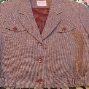 Peut inclure: Un blazer à motif pied-de-poule brun et blanc avec une doublure en satin brun. Le blazer a deux poches à rabat et une fermeture à bouton.