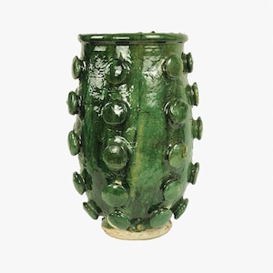 May include: A green ceramic vase with a textured surface and a round base. The vase is decorated with raised circles.