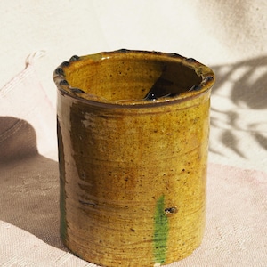 Puede incluir: Un jarr&oacute;n de cer&aacute;mica amarillo con rayas verdes y un borde marr&oacute;n oscuro.