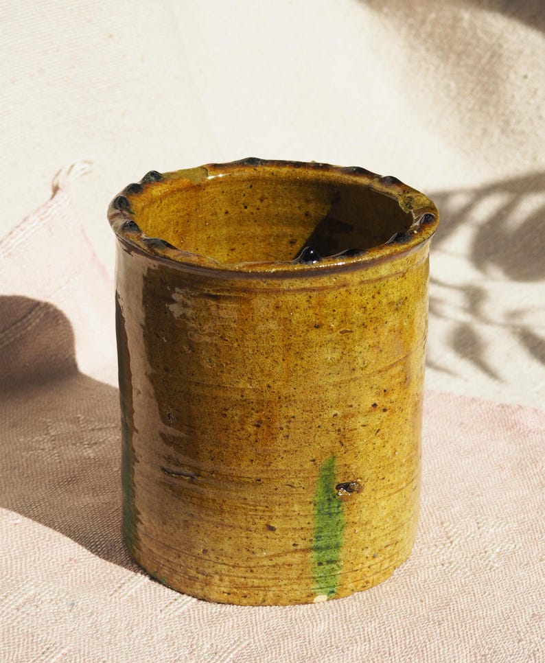 Puede incluir: Un jarr&oacute;n de cer&aacute;mica amarillo con rayas verdes y un borde marr&oacute;n oscuro.