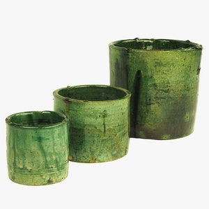 May include: Three green ceramic pots of varying sizes. The pots are glazed in a dark green color with a slightly textured surface.