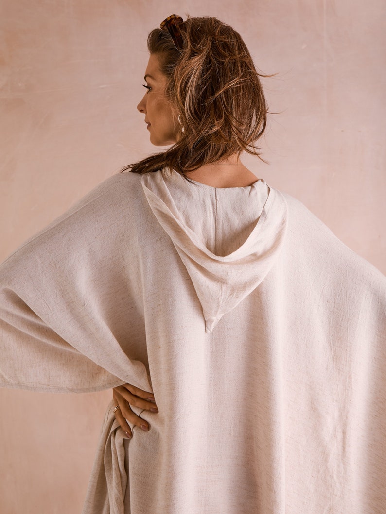 Puede incluir: Una kaftan de lino blanco con capucha y una silueta larga y fluida. La kaftan est&aacute; hecha de una tela ligera y transpirable y tiene un ajuste holgado.