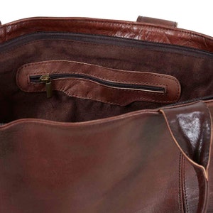 May include: The inside of a brown leather tote bag with a zippered pocket. The bag has a brown suede lining.