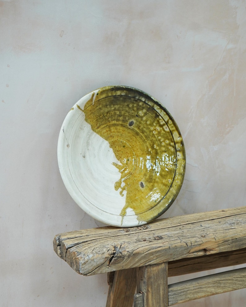 Puede incluir: Un cuenco de cer&aacute;mica hecho a mano con un dise&ntilde;o &uacute;nico. El cuenco es mitad blanco y mitad verde oliva con una superficie texturizada. El cuenco descansa sobre un banco de madera r&uacute;stica. Este cuenco decorativo es ideal para servir alimentos.