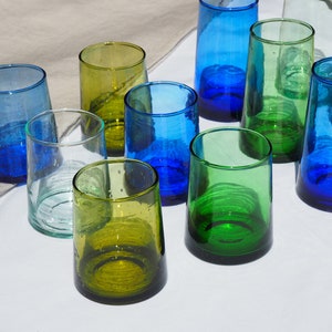 Peut inclure: Dix verres &agrave; boire en verre de diff&eacute;rentes nuances de bleu et de vert. Les verres sont dispos&eacute;s sur une surface blanche.