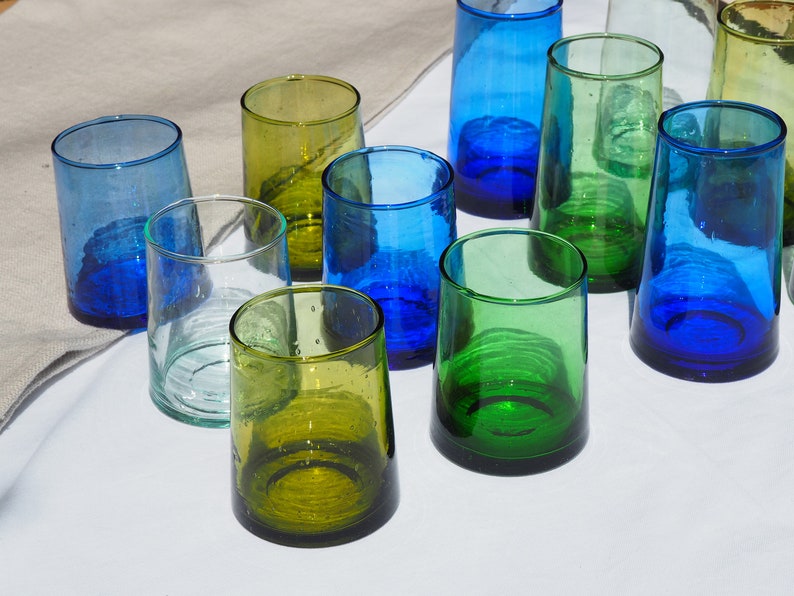 Peut inclure: Dix verres &agrave; boire en verre de diff&eacute;rentes nuances de bleu et de vert. Les verres sont dispos&eacute;s sur une surface blanche.
