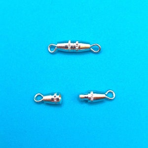 May include: Three silver-toned metal clasps for jewelry making. The clasps are designed to be used with a cord or chain. The clasps are open and ready to be attached to a jewelry piece.