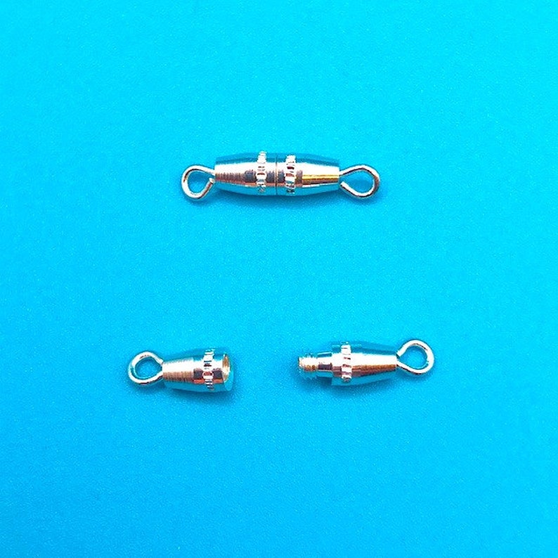 May include: Three silver-toned metal clasps for jewelry making. The clasps are designed to be used with a cord or chain. The clasps are open and ready to be attached to a jewelry piece.