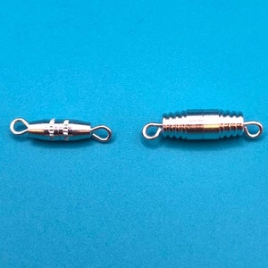 May include: Two silver magnetic clasps for jewelry making. One clasp is a simple design with two loops, the other is a more intricate design with a coiled barrel shape.