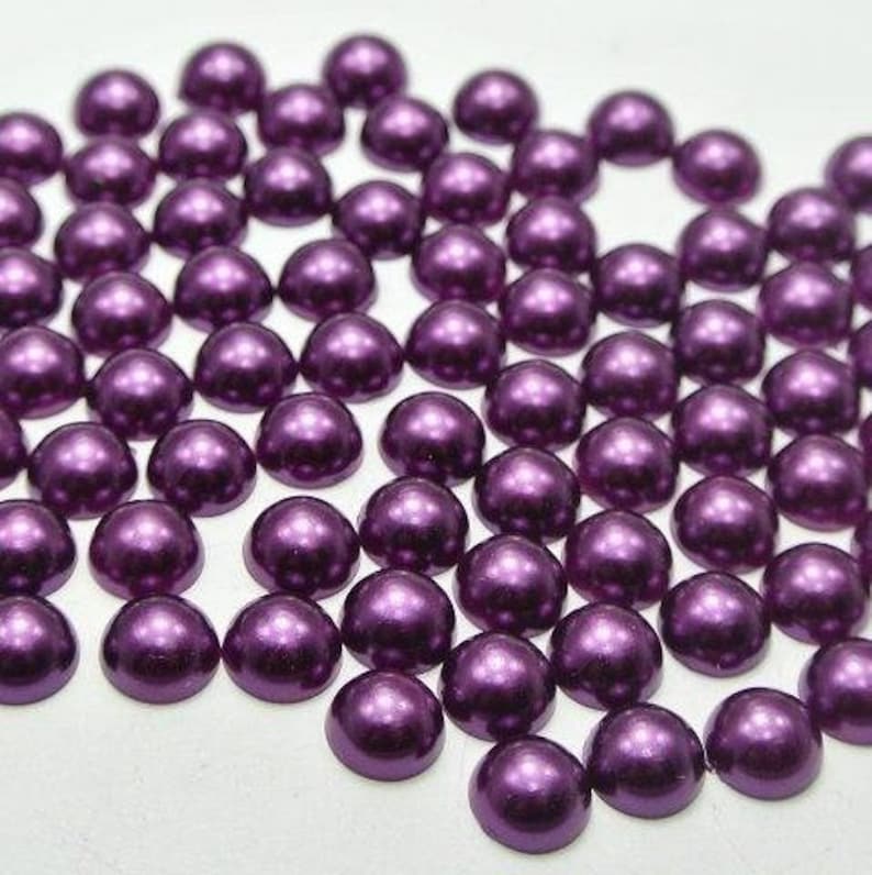 May include: A large quantity of small, round, purple pearl-like beads. The beads have a shiny, metallic finish.