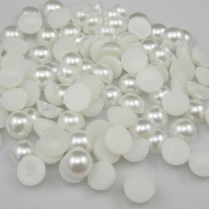 May include: A large quantity of white pearl-like round beads, some with a flat back, for crafting and jewelry making.