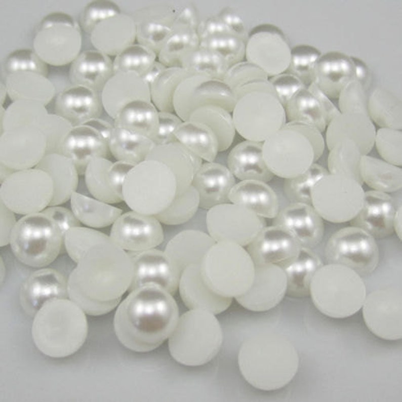 May include: A large quantity of white pearl-like round beads, some with a flat back, for crafting and jewelry making.