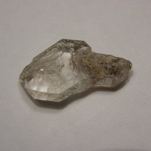 Könnte beinhalten: Ein klarer Quarzkristall mit einer rauen, unregelmäßigen Form. Der Kristall hat ein natürliches, rohes Aussehen und ist ein schönes Beispiel für ein natürliches Mineral.