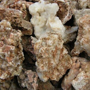 Puede incluir: Primer plano de un mont&oacute;n de rocas &aacute;speras, blancas y marrones. Las rocas tienen una textura cristalina y son de forma irregular.