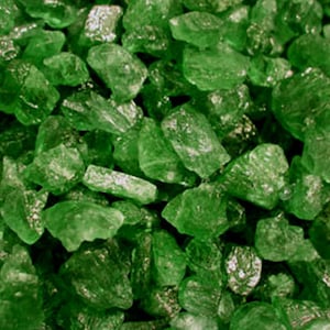 May include: A close-up view of a large quantity of green sugar crystals. The crystals are translucent and have a slightly irregular shape.