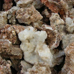 Puede incluir: Primer plano de un mont&oacute;n de rocas &aacute;speras, blancas y marrones. Las rocas tienen una variedad de formas y tama&ntilde;os, y algunas tienen una textura cristalina.