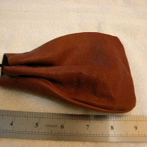 Könnte beinhalten: Ein brauner Lederbeutel mit Kordelzug. Der Beutel ist etwa 20 cm lang.