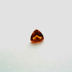 May include: A triangular orange gemstone with a slight yellow hue.