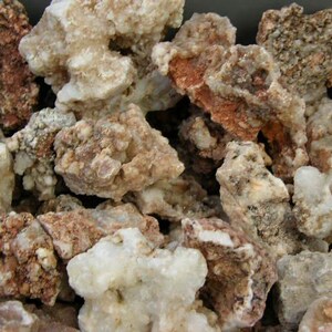 Puede incluir: Primer plano de un mont&oacute;n de rocas &aacute;speras, blancas y marrones. Las rocas tienen una textura cristalina y son de forma irregular.