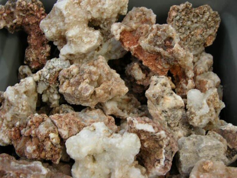 Puede incluir: Primer plano de un mont&oacute;n de rocas &aacute;speras, blancas y marrones. Las rocas tienen una textura cristalina y son de forma irregular.