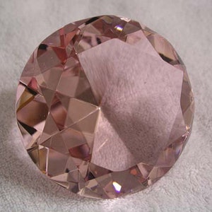 May include: A large, faceted, pink crystal paperweight with a diamond shape.