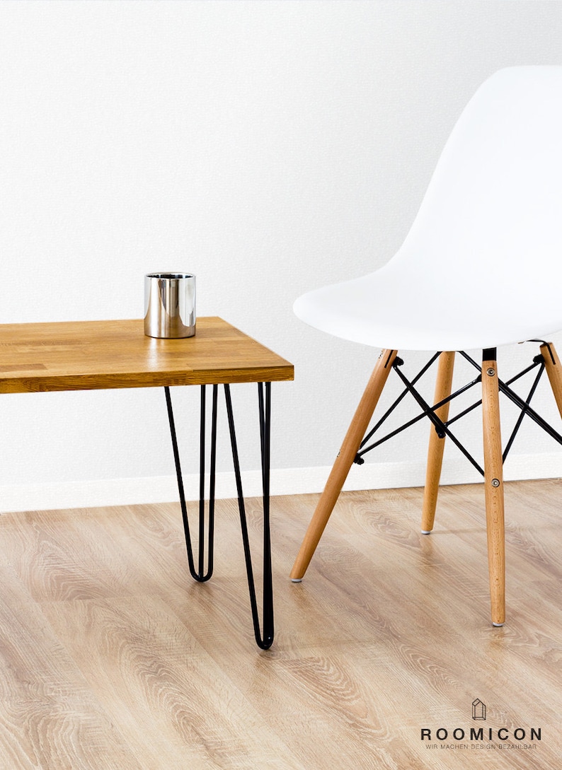 May include: A wooden coffee table with black hairpin legs and a silver metal container on top. The table is next to a white chair with wooden legs.