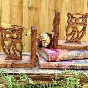May include: A pair of wooden owl bookends with a carved owl design. The bookends are sitting on top of two Harry Potter books, "Harry Potter and the Sorcerer's Stone" and "Harry Potter and the Chamber of Secrets".