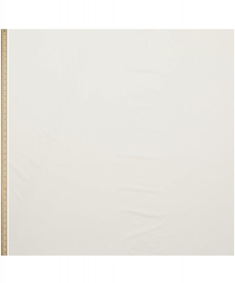 May include: A plain white fabric swatch with a wooden ruler in the left corner.
