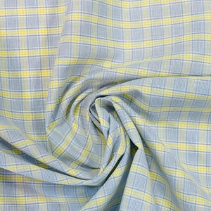 May include: A close-up of a blue and yellow plaid fabric. The fabric is folded and draped, showing the texture and pattern.
