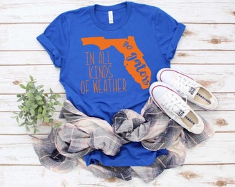 May include: A royal blue t-shirt with an orange outline of the state of Florida and the text "Go Gators" and "In all kinds of weather".