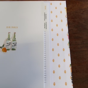 May include: A white binder page with the text DRINKS and an illustration of two bottles and an orange. The page features vertical tabs labeled Drinks, Breakfast & Baked Goods, and Condiments & Sauces. Text reads: Standard tabs: pages in sheet protectors will cover the tabs.