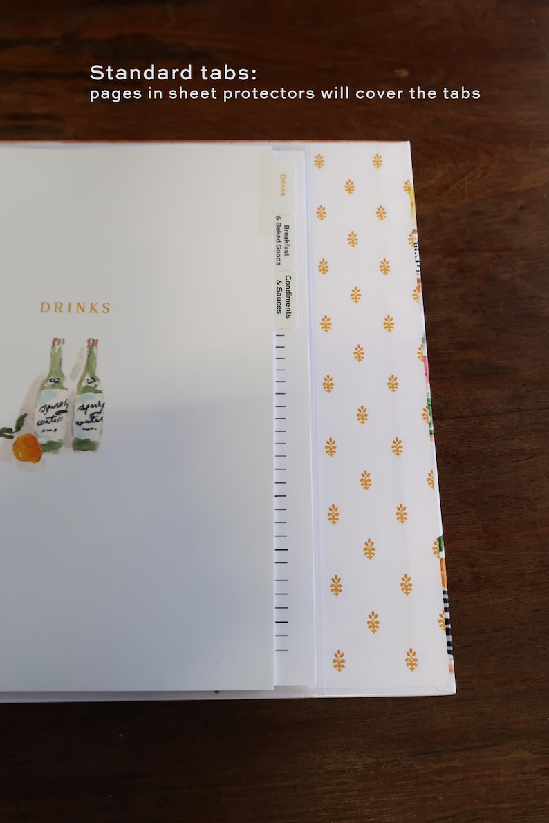 May include: A white binder page with the text DRINKS and an illustration of two bottles and an orange. The page features vertical tabs labeled Drinks, Breakfast & Baked Goods, and Condiments & Sauces. Text reads: Standard tabs: pages in sheet protectors will cover the tabs.