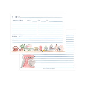 May include: Two white recipe cards with blue lines. The top card features a kitchen shelf illustration with a kettle, plant, cake stand, and coffee press. The bottom card displays a pink stand mixer. Both cards include the text THEILLUSTRATEDLIFE.CO.