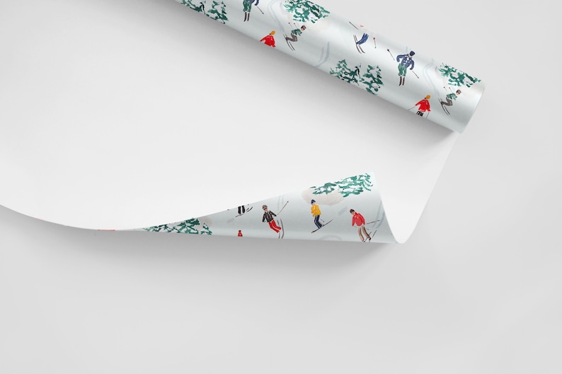 May include: A roll of white wrapping paper with a repeating pattern of skiers in colorful clothing on a snowy mountain landscape. The paper is partially unrolled, revealing the pattern.