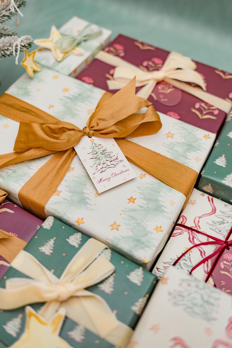 May include: A collection of wrapped Christmas gifts with various patterned papers, including watercolor trees and floral designs. Each gift is tied with a ribbon and bow, some with gift tags that read "Merry Christmas".