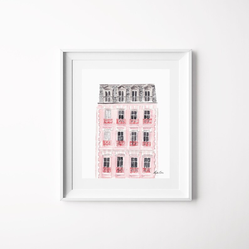 Puede incluir: Una pintura de acuarela de un edificio rosa con un techo gris y balcones rojos. El edificio tiene varias ventanas y est&aacute; pintado en un estilo suave y rom&aacute;ntico.