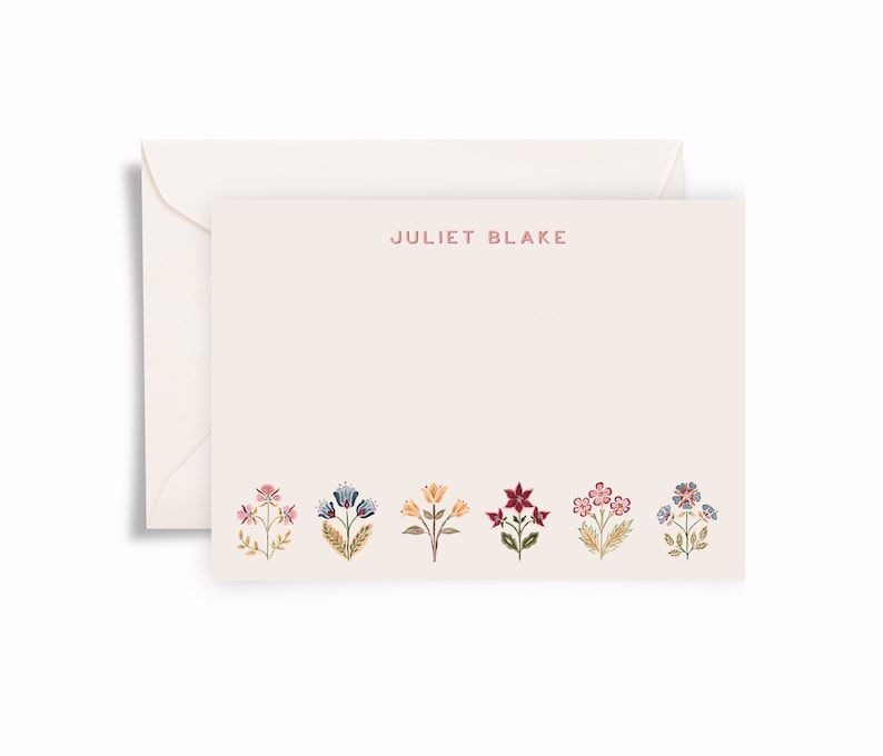 May include: A cream-coloured stationery card and matching envelope. The card features the name JULIET BLAKE printed in red at the top centre and a row of six colourful, detailed floral illustrations in shades of pink, blue, yellow, and red.