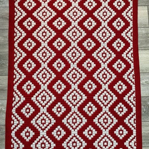 May include: Red and white crocheted rug with a geometric diamond pattern.