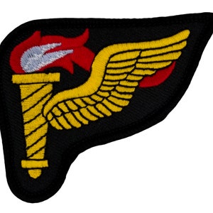May include: A black embroidered patch with a yellow winged torch. The torch has a red flame and a white center.