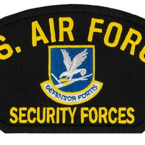 May include: A black patch with yellow embroidered text that reads "U.S. AIR FORCE SECURITY FORCES". A blue and yellow shield with a white bird is in the center of the patch.