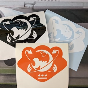 May include: Three vinyl stickers with a white design of a stylized creature with arrows on a black, blue, and orange background.