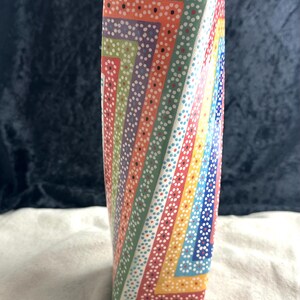 May include: A colorful ceramic vase with a geometric pattern of dots and lines in shades of green, orange, yellow, blue, and pink.