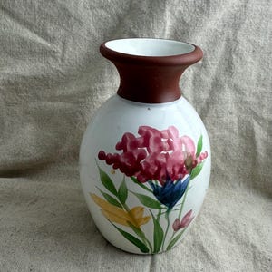Puede incluir: Jarr&oacute;n de cer&aacute;mica blanca con cuerpo bulboso y cuello marr&oacute;n oscuro. El jarr&oacute;n est&aacute; pintado a mano con un dise&ntilde;o floral con flores rosas, azules y amarillas con hojas verdes. Una pieza decorativa para la decoraci&oacute;n del hogar.