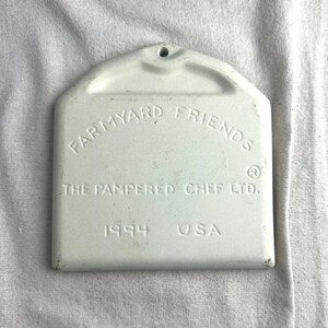May include: White ceramic baking dish with the text "Farmyard Friends The Pampered Chef Ltd. 1994 USA" on the bottom.