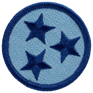 May include: Embroidered patch featuring three dark blue stars arranged in a triangular pattern on a light blue background. The patch is circular with a dark blue border, showcasing a detailed, textured design.