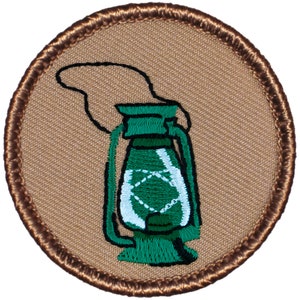 May include: A green lantern with a brown border, embroidered on a tan fabric background.