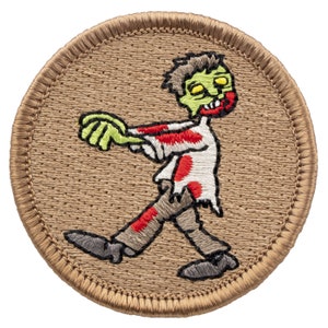 May include: A round, tan embroidered patch with a cartoon zombie walking. The zombie is green with red and white clothing. The zombie has yellow eyes and a red mouth.
