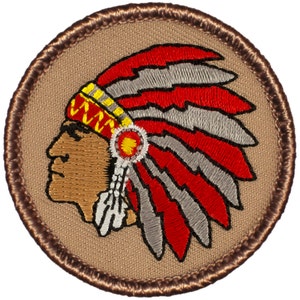 May include: Embroidered patch featuring a Native American chief wearing a red and gray headdress with white feathers. The patch is circular and has a brown border.